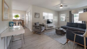 Uma sala de estar moderna com sofá, poltrona e área de jantar com mesa e cadeiras.