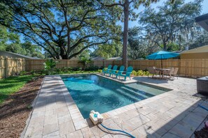 A backyard with a swimming pool, a wooden fence, and a patio area with outdoor furniture. - Cozy Retreat w/ Heated Pool & Yard Near Downtown (Tampa)