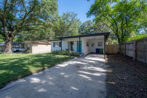 A single-story house with a front porch, a small attached garage, and a fenced backyard.