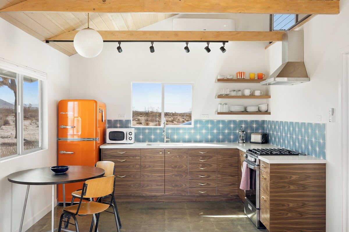 A compact kitchen with a wooden ceiling, a built-in microwave, a stove, and a window with a view.