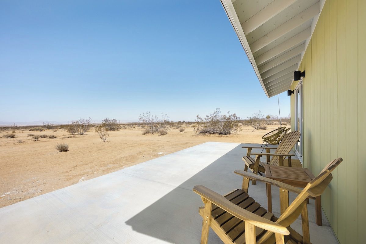 Eine Terrasse mit Holzstühlen und einem Tisch, mit Blick auf eine Wüstenlandschaft.