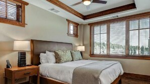 Ein Schlafzimmer mit einem großen Bett, einem Holzkopfteil, zwei Nachttischlampen, einem Nachttisch und einem Deckenventilator.