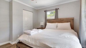 A neatly made bed with white linens, a wooden headboard, and a ceiling fan.