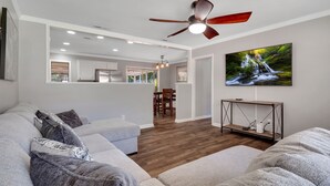 A modern living room with a grey sofa, a wooden coffee table, and a ceiling fan.