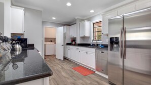 A modern kitchen with white cabinets, a stainless steel refrigerator, and a granite countertop.