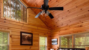 A wooden cabin bedroom with a bed, ceiling fan, windows, and a framed picture on the wall. - Cabin Blue Ridge-Murphy area, fast wifi, dog & family friendly, trail & hot tub! (Murphy)