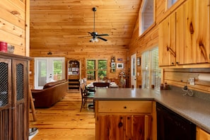 A wooden cabin interior with a dining area, kitchen, and a ceiling fan. - Cabin Blue Ridge-Murphy area, fast wifi, dog & family friendly, trail & hot tub! (Murphy)