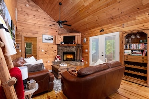 A cozy cabin interior with a fireplace, leather furniture, and a bookshelf. - Cabin Blue Ridge-Murphy area, fast wifi, dog & family friendly, trail & hot tub! (Murphy)