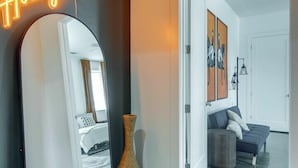 A modern interior with a neon sign, a large mirror, a cowhide rug, and a doorway leading to another room.