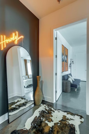 Un intérieur moderne agrémenté d’un néon, d’un grand miroir, d’un tapis en peau de vache et d’un passage menant à une autre pièce.