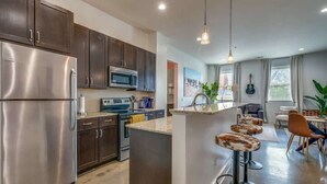 A modern kitchen with dark cabinets, stainless steel appliances, and a central island with bar stools.