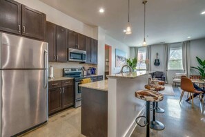Una cocina moderna con armarios oscuros, electrodomésticos de acero inoxidable y una isla central con taburetes de bar.