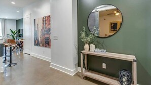 A hallway with a reception desk, a mirror, a welcome sign, and a plant.