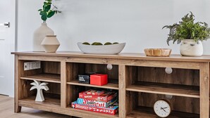 A wooden console table with a bowl of green balls, a potted plant, and a clock. - Casa Del Sol - Bike to Beach, Saltwater Pool & Private Backyard (Palm Beach Gardens)