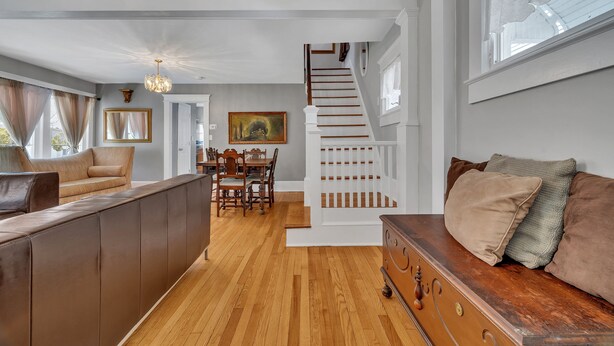 A spacious living area with a wooden staircase, a dining table, and a sofa.