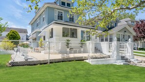 A two-story house with a covered patio, a fenced yard, and a well-maintained lawn.