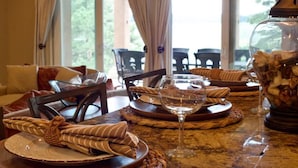 A dining table set with plates, a wine glass, and a decorative jar. - Mountain Luxury and Views Galore Near Palmer Lake (Larkspur)