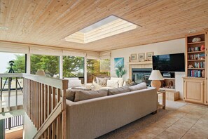 A spacious living room with a large sofa, a television, and a bookshelf.
