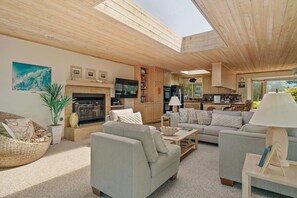 A spacious living area with a fireplace, sofas, a television, and a skylight.