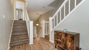 A wooden staircase leading to a landing with a white railing and a wooden cabinet with drawers.