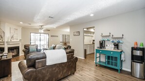 A spacious living room with a fireplace, leather sofas, and a coffee bar.