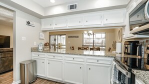 A modern kitchen with white cabinetry, a granite countertop, and stainless steel appliances.
