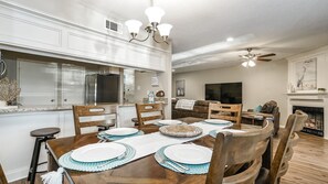 Un coin repas avec une table en bois dressée pour quatre personnes, entourée de chaises en bois.