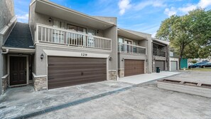 Un immeuble résidentiel de deux étages, doté d’un garage portant le numéro 129, d’un balcon à l’étage supérieur et d’une allée menant à une grille métallique.