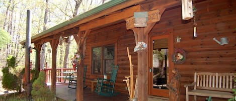 A rustic cabin with a porch, rocking chairs, and a wooden bench.