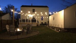 A backyard with a fire pit, outdoor seating, and string lights. - Cozy and completely updated The Farmhouse at Lanterman's Village (Youngstown)