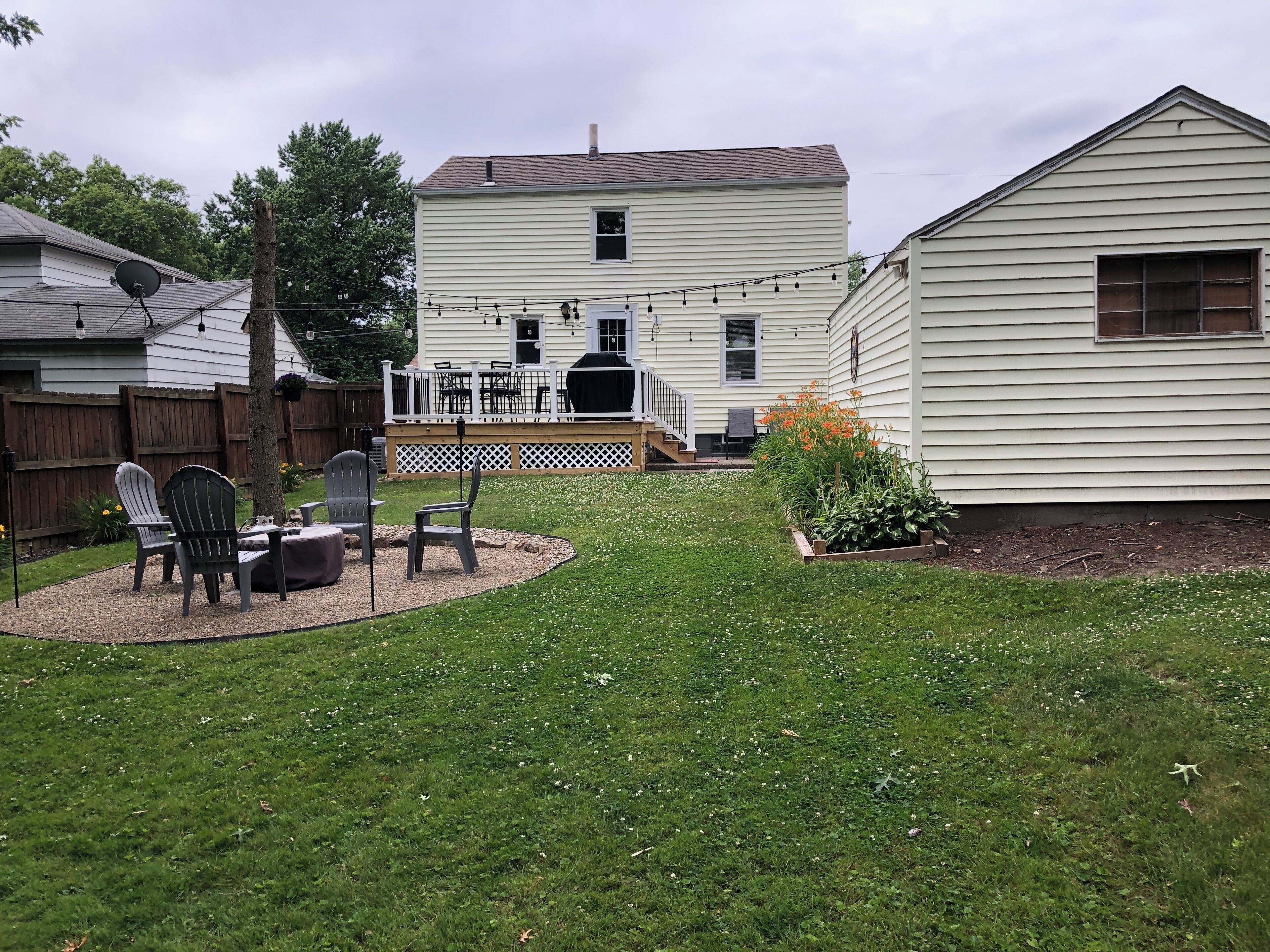A backyard with a patio area, a deck, and a house.