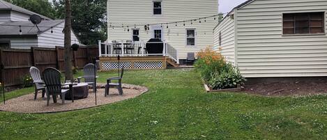 A backyard with a patio area, a deck, and a house.