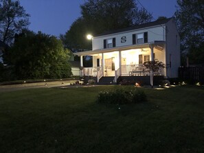 Una casa de dos pisos con un porche, un jardín delantero y un farol.
