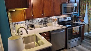 A modern kitchen with wooden cabinets, stainless steel appliances, and a tiled backsplash. - Cozy and completely updated The Farmhouse at Lanterman's Village (Youngstown)