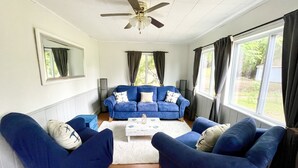 Una sala de estar con un sofá azul, una mesa de centro blanca y un ventilador de techo.