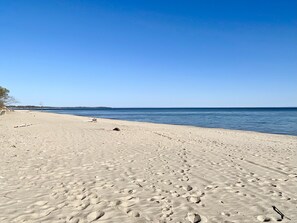 Une plage de sable avec des empreintes et un ciel bleu clair.