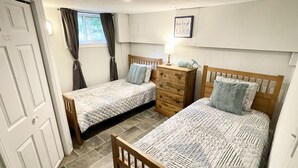 Un dormitorio con dos camas, un aparador, una ventana con cortinas y un letrero en la pared.