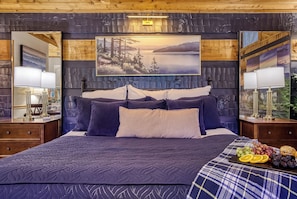 A bedroom with a large bed, two bedside tables, a nightstand, a painting, and a fruit basket.