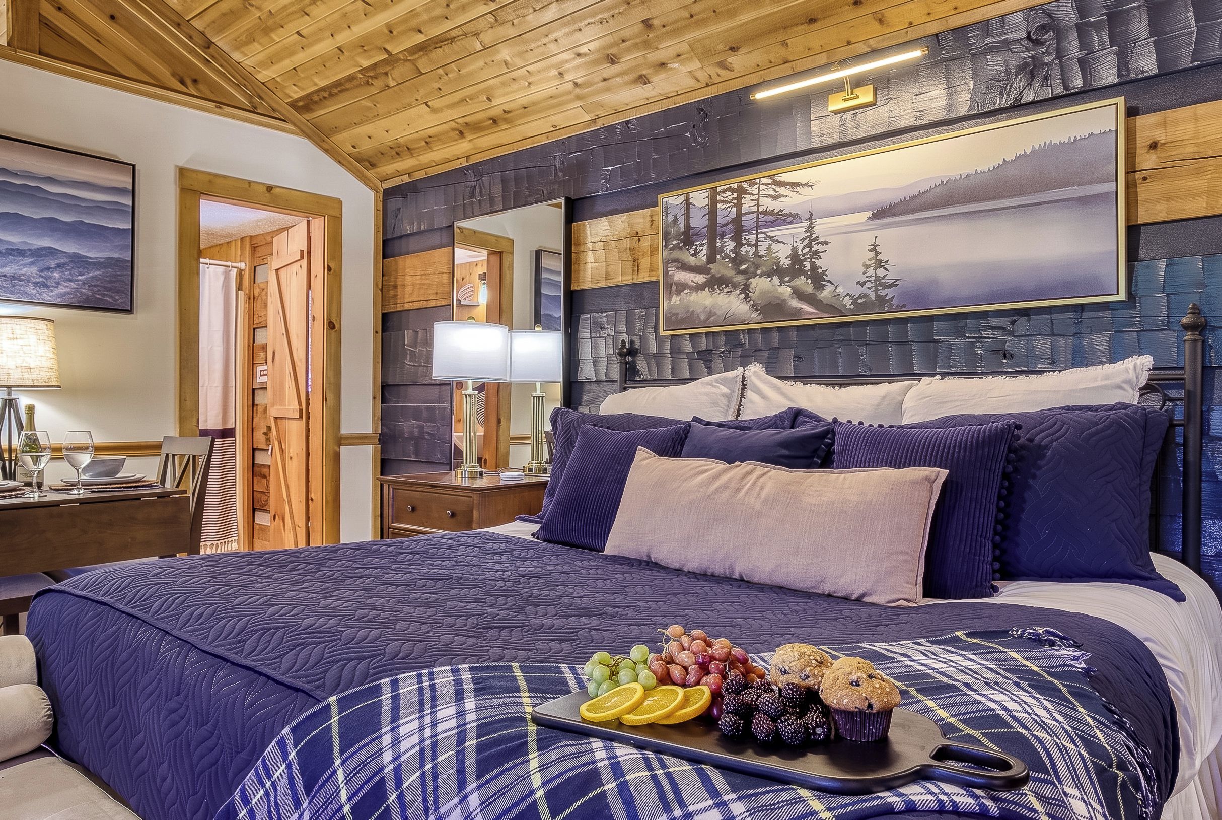 Een slaapkamer met een groot bed, een houten plafond en een schilderij van een berglandschap aan de muur.
