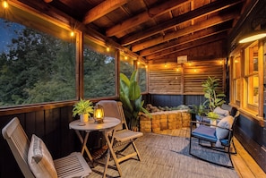 A cozy outdoor seating area with wooden furniture, string lights, and a view of the forest. - Couple's Hot Tub Cabin-King Bed • 10 Min Dollywood (Sevierville)