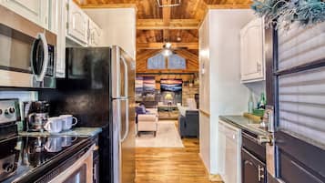 Una cocina moderna con electrodomésticos de acero inoxidable, techo de madera y chimenea de piedra.