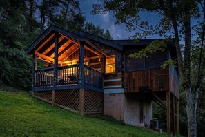 Eine Holzhütte mit einer Holzterrasse, einer überdachten Veranda und einem großen Fenster.
