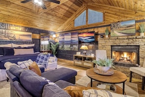 A cozy living room with a fireplace, a large sofa, a coffee table, and a television.