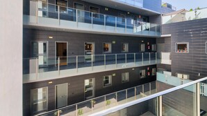 A multi-story building with a modern design, featuring balconies, large windows, and a glass railing.