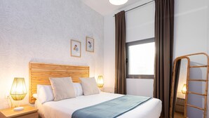 A neatly arranged hotel room with a wooden bed, two bedside lamps, a window with curtains, and a mirror.