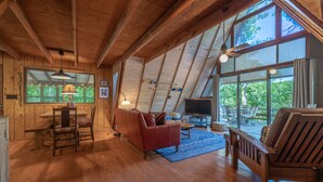 A spacious loft with wooden beams, large windows, a dining area, and a cozy seating area.
