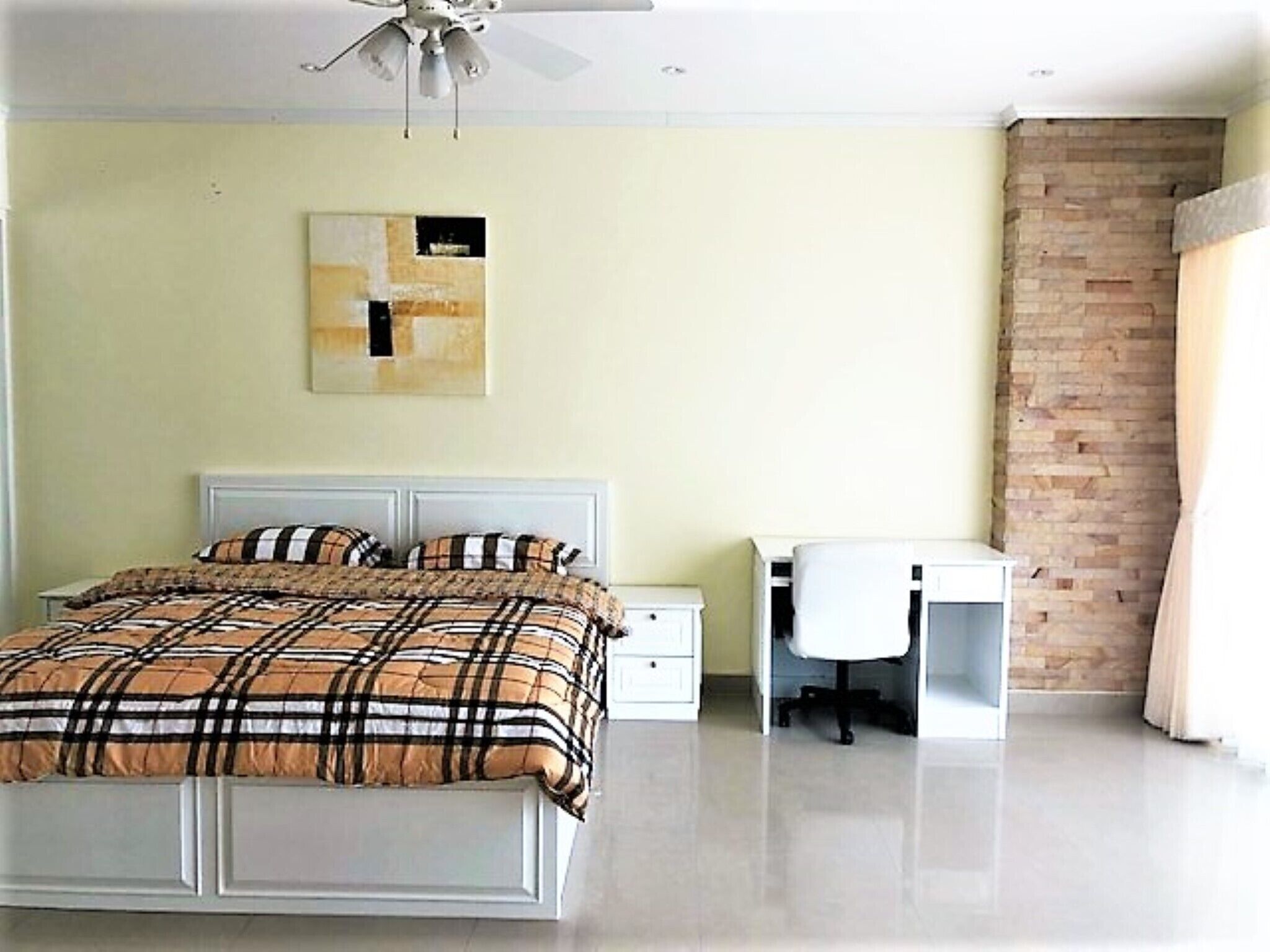 A bedroom with a bed, a desk, and a chair.