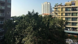 Un immeuble à plusieurs étages, doté de balcons, avec un arbre touffu en premier plan.