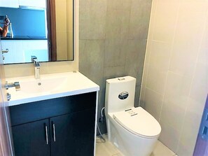 Une salle de bain avec un lavabo blanc, des meubles sombres et des toilettes.
