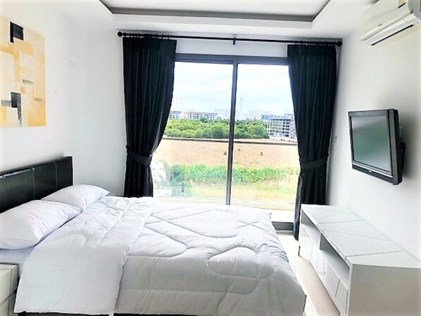 Hotelkamer met een groot bed, een aan de muur bevestigde televisie en uitzicht op een stadsgezicht.